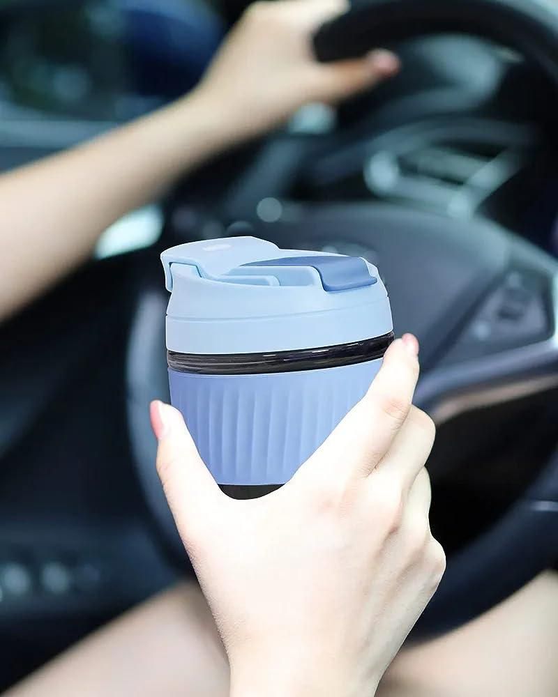 Person holding a blue travel mug inside a car
